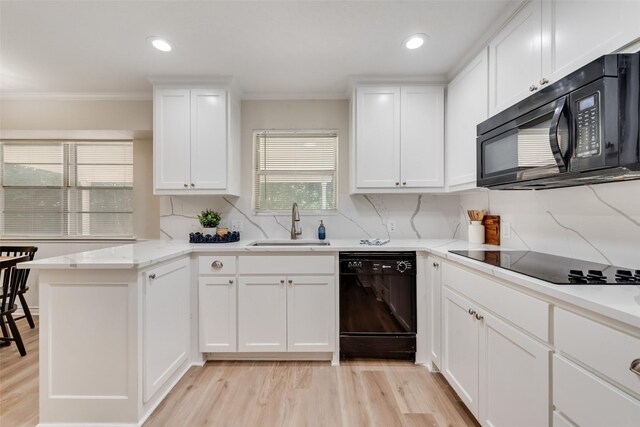 5504 Whitman Ave, Fort Worth, TX 76133 - kitchen featuring black appliances, a peninsula, light wood-style flooring, crown molding, and white cabinets
