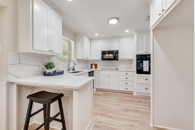 5504 Whitman Ave, Fort Worth, TX 76133 - kitchen with black appliances, a peninsula, white cabinetry, light wood finished floors, and recessed lighting