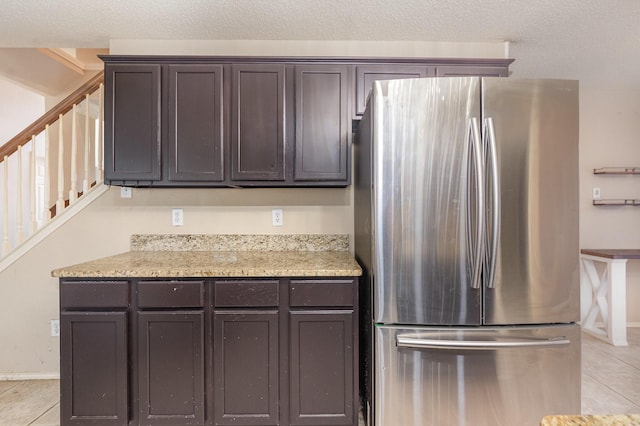 2120 Valley Falls Ave, Mesquite, TX 75181 - kitchen featuring freestanding refrigerator, dark brown cabinetry, light tile patterned floors, and light stone counters