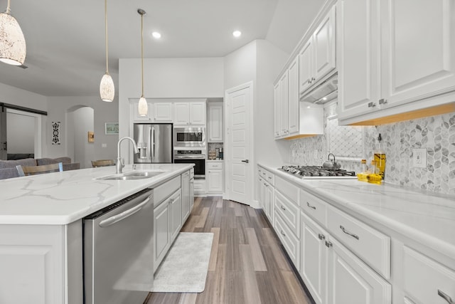 9424 Excursion Dr, Oak Point, TX 75068 - kitchen featuring stainless steel appliances, arched walkways, wood finished floors, white cabinetry, and recessed lighting