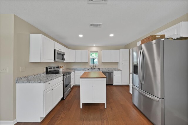 3767 Matson St, North Richland Hills, TX 76117 - kitchen with stainless steel appliances, dark wood-type flooring, a kitchen island, white cabinetry, and butcher block counters