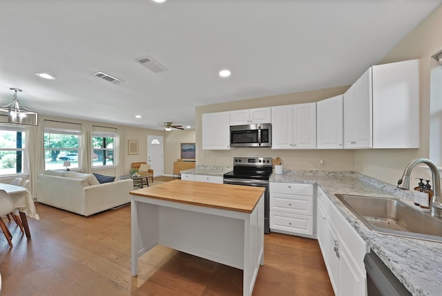 3767 Matson St, North Richland Hills, TX 76117 - kitchen with appliances with stainless steel finishes, butcher block countertops, open floor plan, white cabinets, and recessed lighting