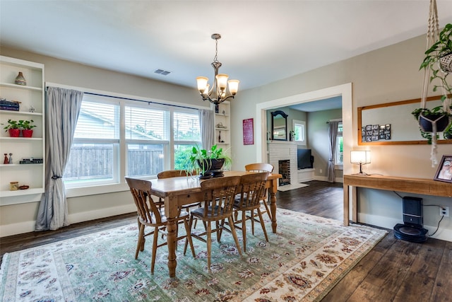 2324 Lynnhaven Rd, Fort Worth, TX 76103 - dining space featuring healthy amount of natural light, a chandelier, wood finished floors, and a fireplace