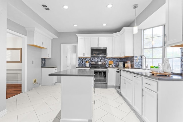 1092 Rosewood Dr, Grapevine, TX 76051 - kitchen featuring stainless steel appliances, dark countertops, a kitchen island, backsplash, and white cabinetry