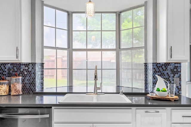 1092 Rosewood Dr, Grapevine, TX 76051 - kitchen with stainless steel dishwasher, dark countertops, white cabinetry, and tasteful backsplash