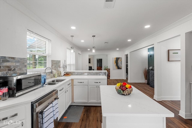 107 Preston Ave, Shreveport, LA 71105 - kitchen featuring stainless steel microwave, dark wood-style flooring, ornamental molding, white cabinetry, and decorative light fixtures