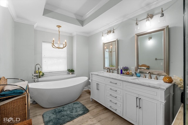 107 Preston Ave, Shreveport, LA 71105 - full bath featuring a chandelier, double vanity, a freestanding tub, a tray ceiling, and wood finished floors
