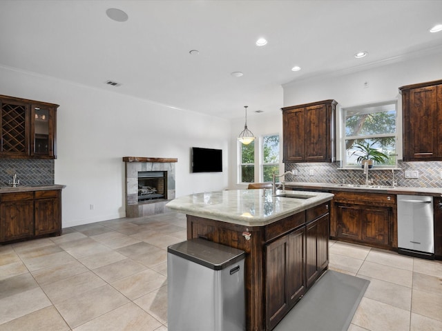 186 Deer Creek Dr, Aledo, TX 76008 - kitchen featuring backsplash, light tile patterned floors, a tile fireplace, an island with sink, and dark brown cabinets