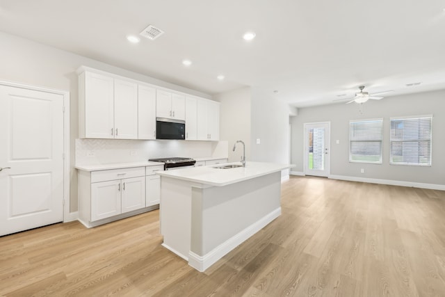 505 Willet Dr, Mckinney, TX 75069 - kitchen featuring stainless steel microwave, ceiling fan, backsplash, light wood-style flooring, and a center island with sink