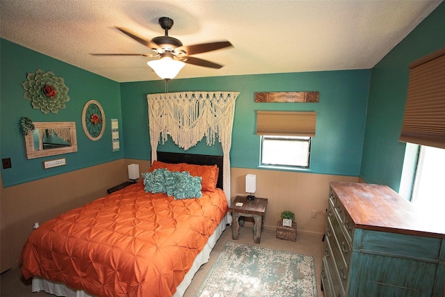 10234 County Road 198, Breckenridge, TX 76424 - carpeted bedroom featuring multiple windows, wainscoting, a textured ceiling, and a ceiling fan