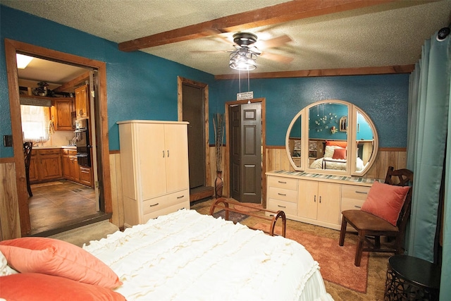 10234 County Road 198, Breckenridge, TX 76424 - bedroom with a wainscoted wall, a textured ceiling, wooden walls, and beam ceiling