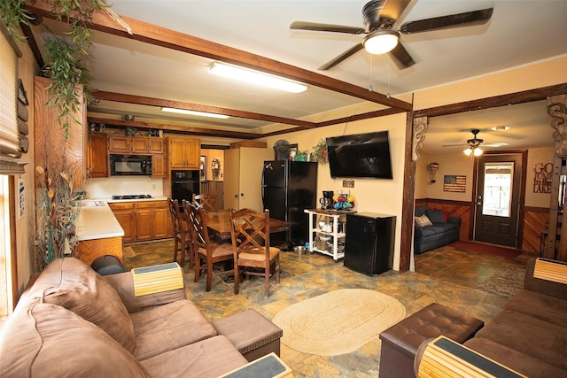 10234 County Road 198, Breckenridge, TX 76424 - living room with a ceiling fan, beamed ceiling, a wainscoted wall, and dark stone finish flooring