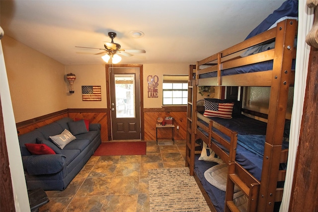 10234 County Road 198, Breckenridge, TX 76424 - living area featuring a wainscoted wall, stone finish floors, wooden walls, and ceiling fan