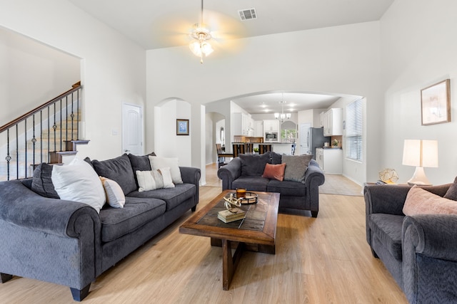 584 Indian Hill Dr, Oak Point, TX 75068 - living area featuring arched walkways, light wood-style flooring, ceiling fan, a towering ceiling, and stairs