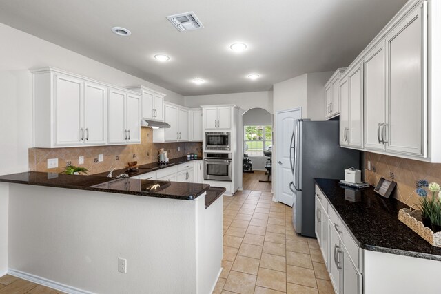 584 Indian Hill Dr, Oak Point, TX 75068 - kitchen featuring appliances with stainless steel finishes, arched walkways, a peninsula, white cabinets, and recessed lighting