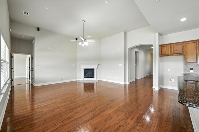 8120 Tyler Dr, Lantana, TX 76226 - unfurnished living room featuring arched walkways, ceiling fan, dark wood-style floors, a glass covered fireplace, and recessed lighting