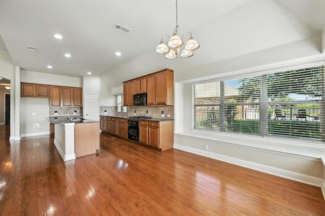 8120 Tyler Dr, Lantana, TX 76226 - kitchen with black appliances, dark countertops, a chandelier, decorative backsplash, and brown cabinets