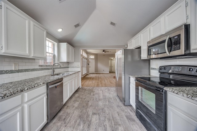 2102 Overview Ln, Garland, TX 75044 - kitchen featuring appliances with stainless steel finishes, white cabinetry, light wood-type flooring, tasteful backsplash, and lofted ceiling