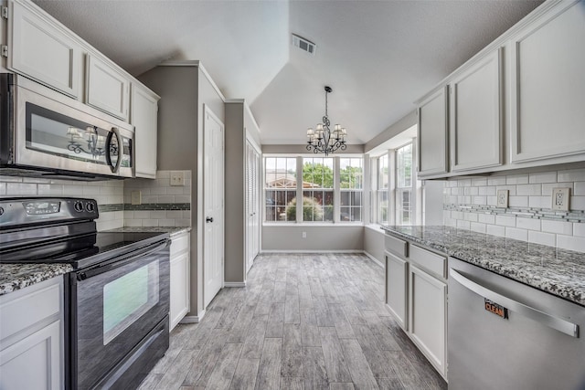 2102 Overview Ln, Garland, TX 75044 - kitchen with appliances with stainless steel finishes, a chandelier, light wood-style flooring, vaulted ceiling, and backsplash