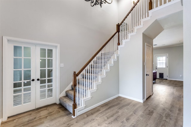 17712 Meadow Grove Ln, Dallas, TX 75287 - stairway featuring french doors, wood finished floors, a high ceiling, crown molding, and a chandelier