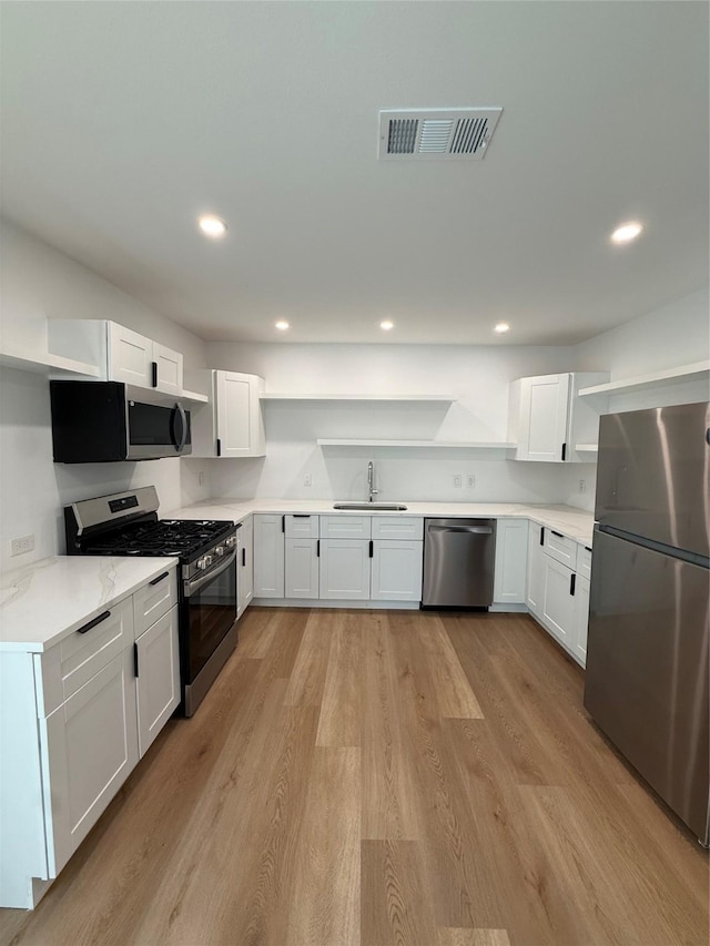 1019 E Waco Ave, Dallas, TX 75216 - kitchen with open shelves, stainless steel appliances, white cabinetry, light wood finished floors, and recessed lighting