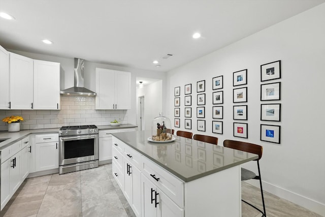 1415 W St, Mckinney, TX 75069 - kitchen with wall chimney exhaust hood, stainless steel gas range oven, a breakfast bar area, backsplash, and a kitchen island