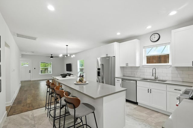 1415 W St, Mckinney, TX 75069 - kitchen with appliances with stainless steel finishes, a center island, open floor plan, a kitchen bar, and white cabinetry