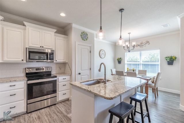 7309 Wildflower Way, Abilene, TX 79602 - kitchen featuring appliances with stainless steel finishes, light wood finished floors, tasteful backsplash, a chandelier, and ornamental molding