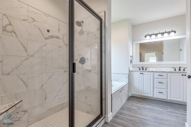 7309 Wildflower Way, Abilene, TX 79602 - bathroom with a marble finish shower, a bath, double vanity, and wood finished floors