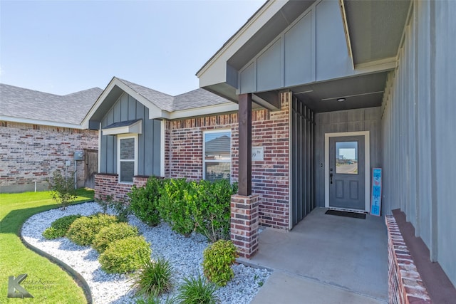7309 Wildflower Way, Abilene, TX 79602 - doorway to property with board and batten siding, brick siding, and roof with shingles