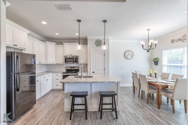 7309 Wildflower Way, Abilene, TX 79602 - kitchen with appliances with stainless steel finishes, ornamental molding, light wood finished floors, white cabinetry, and tasteful backsplash