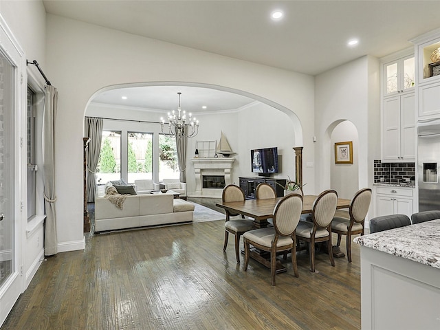 13002 Terlingua Creek Dr, Frisco, TX 75033 - dining space featuring arched walkways, dark wood-type flooring, recessed lighting, a high end fireplace, and a chandelier