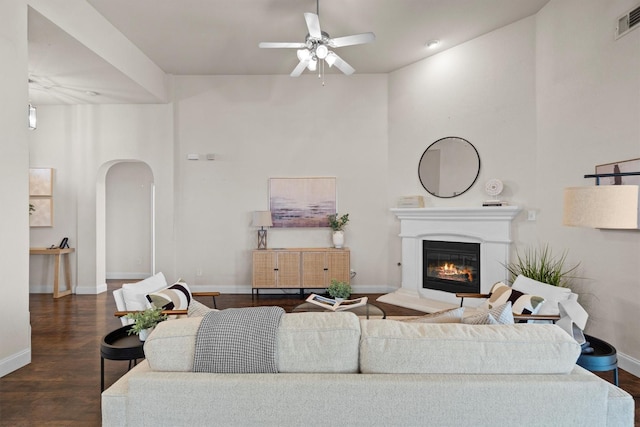 60 N Highland Dr, Sanger, TX 76266 - living room featuring a ceiling fan, arched walkways, dark wood finished floors, and a glass covered fireplace