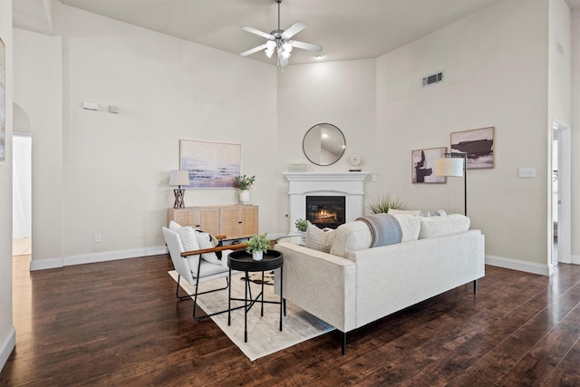 60 N Highland Dr, Sanger, TX 76266 - living area featuring a ceiling fan, wood finished floors, a glass covered fireplace, a high ceiling, and arched walkways
