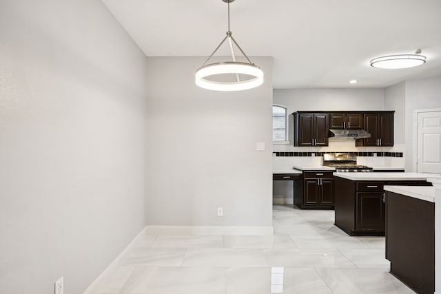 433 Willow Bend Dr, Murphy, TX 75094 - kitchen with light countertops, under cabinet range hood, backsplash, dark brown cabinets, and decorative light fixtures