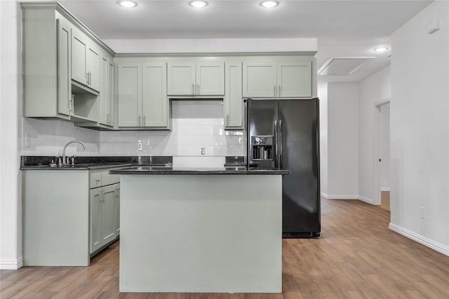 2522 Refugio Ave, Fort Worth, TX 76164 - kitchen featuring black fridge with ice dispenser, dark countertops, a kitchen island, wood finished floors, and recessed lighting