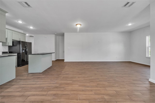 2522 Refugio Ave, Fort Worth, TX 76164 - kitchen with black fridge, dark countertops, light wood-style floors, recessed lighting, and a kitchen island