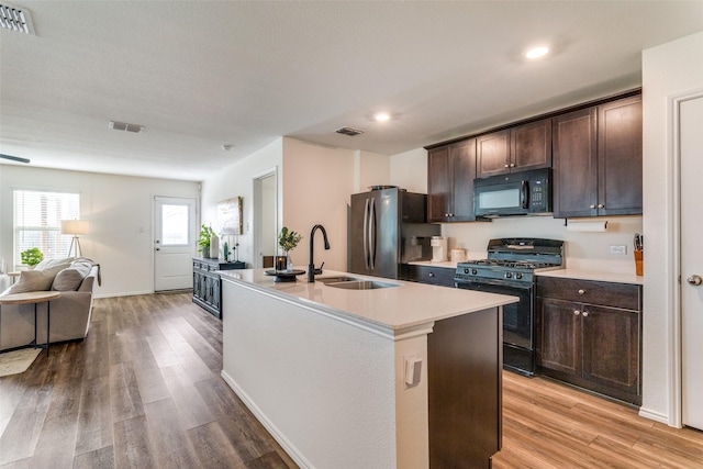 14304 Saddlebred Way, Fort Worth, TX 76052 - kitchen with black appliances, dark brown cabinets, light wood finished floors, light countertops, and recessed lighting