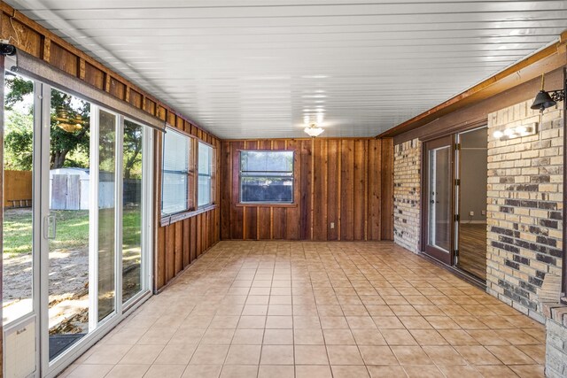 5207 Atlantis Ter, Arlington, TX 76016 - unfurnished sunroom with wooden walls, brick wall, and tile patterned flooring