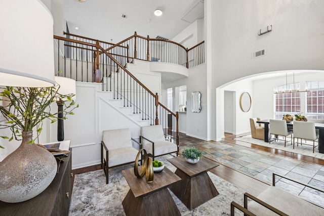 5725 Gerber Ter, Plano, TX 75094 - living room featuring a high ceiling, stairs, a chandelier, and arched walkways