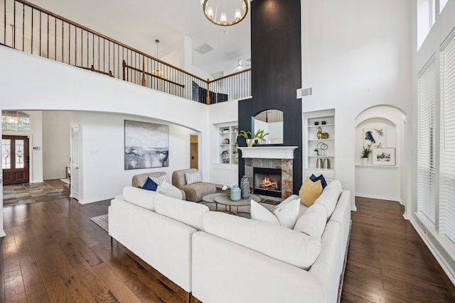 5725 Gerber Ter, Plano, TX 75094 - living room with a high ceiling, built in shelves, dark wood finished floors, a stone fireplace, and a chandelier