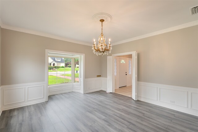 601 N 25th St, Corsicana, TX 75110 - empty room with a chandelier, ornamental molding, a wainscoted wall, a decorative wall, and wood finished floors