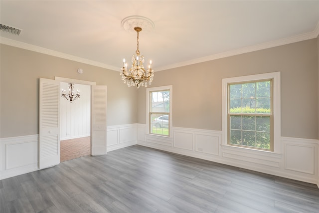 601 N 25th St, Corsicana, TX 75110 - empty room featuring a chandelier, a wainscoted wall, dark wood-style flooring, ornamental molding, and a decorative wall