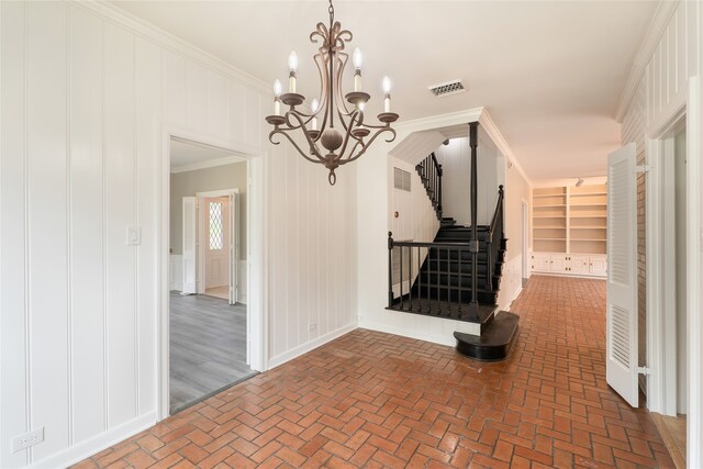601 N 25th St, Corsicana, TX 75110 - spare room with brick floors, crown molding, a chandelier, stairway, and a decorative wall