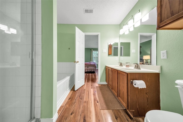 1032 Hampton Dr, Forney, TX 75126 - ensuite bathroom with wood finished floors, a garden tub, an enclosed shower, double vanity, and a textured ceiling