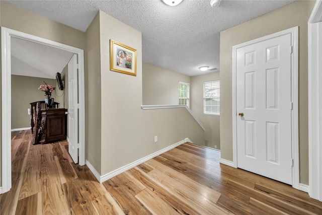 1032 Hampton Dr, Forney, TX 75126 - hallway featuring a textured ceiling, wood finished floors, and an upstairs landing