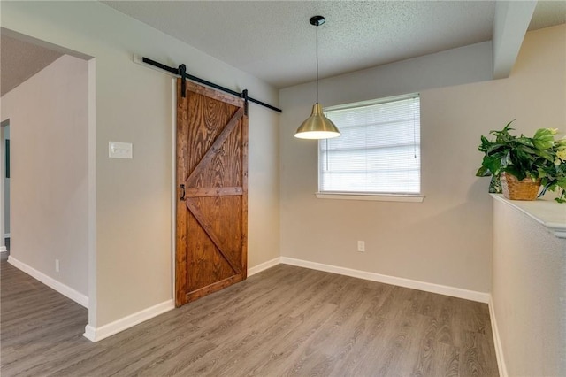 7820 Kermit Ave, Fort Worth, TX 76116 - unfurnished dining area with a barn door, wood finished floors, and a textured ceiling