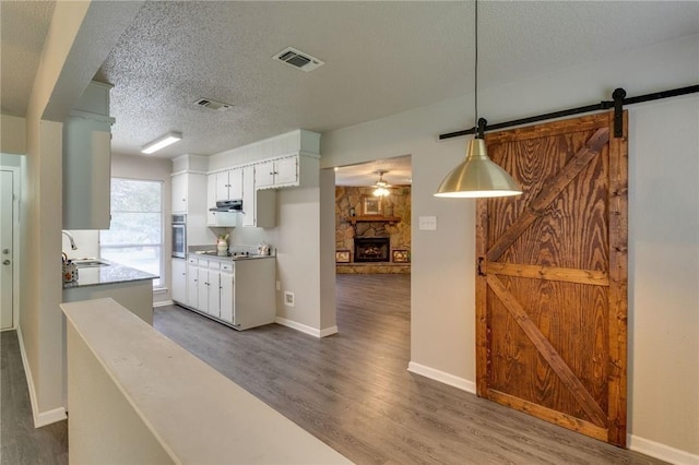 7820 Kermit Ave, Fort Worth, TX 76116 - kitchen with stainless steel oven, dark wood-type flooring, black electric cooktop, a ceiling fan, and a barn door