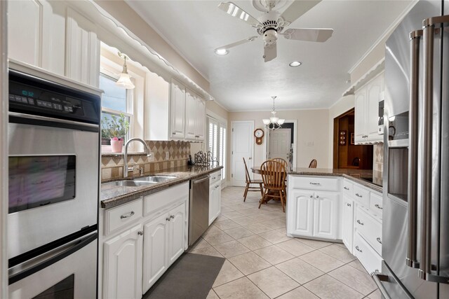 10707 Ferndale Rd, Dallas, TX 75238 - kitchen with stainless steel appliances, a peninsula, decorative backsplash, white cabinets, and a ceiling fan
