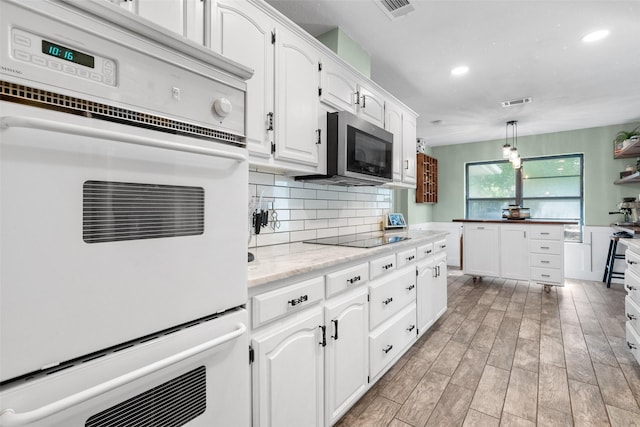 1322 Chestnut Rd, Mansfield, TX 76063 - kitchen featuring stainless steel microwave, black electric cooktop, white cabinets, recessed lighting, and backsplash